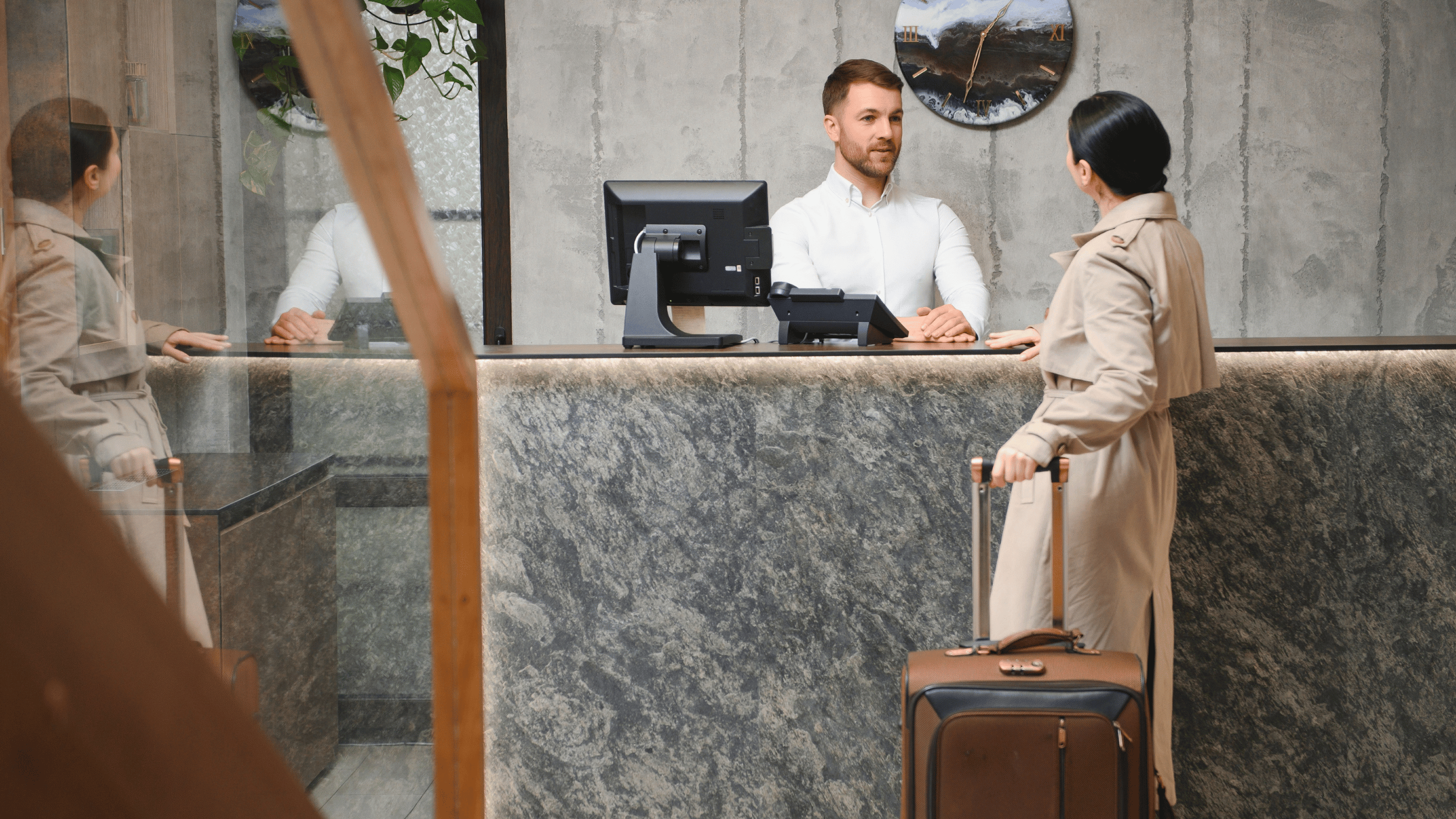 A hotel desk associate assists a guest at the front desk – Aven Hospitality