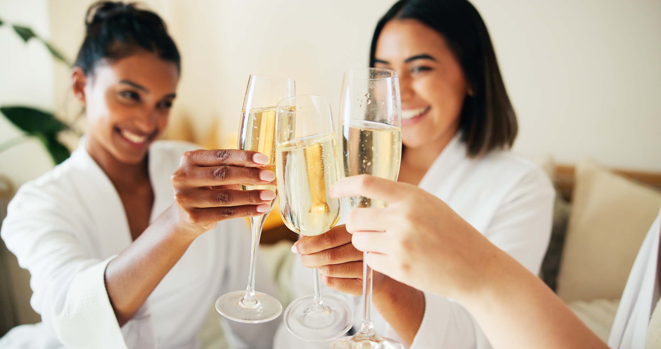 Women at a hotel cheers champagne glasses - Aven Hospitality